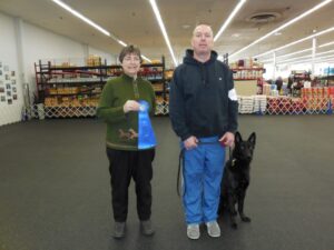 Man, woman, and dog posing with first place ribbon