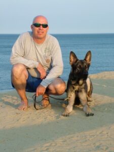 Man and German Shepard posing on Cape Cod beach